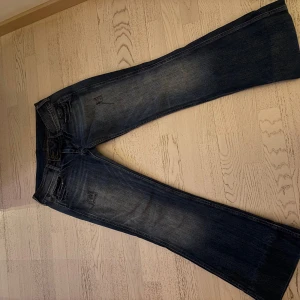 Blå bootcut jeans - Snygga blå bootcut jeans med slitna detaljer och klassisk femficksdesign. Perfekta för en avslappnad stil med en touch av vintagekänsla. De har en knappgylf och är tillverkade i ett robust denimtyg. Midjemåttet rakt över: 43cm. Benlängden rakt ner: 94,5cm💕💕
