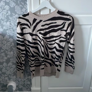 Zebramönstrad tröja från M&S Collection - Snygg zebramönstrad tröja från M&S Collection i beige och svart. Tröjan har långa ärmar och en rund halsringning.