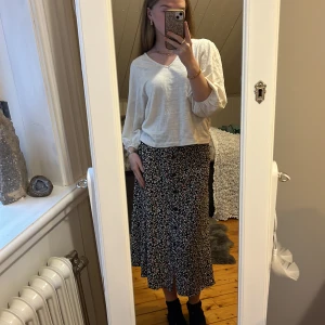 Blommig kjol från b.young - Säljer en fin blommig kjol från b.young i storlek 34. Kjolen har ett svart basmönster med små blommor i rosa, gult och vitt. Den är knälång och har knappar framtill för en snygg detalj. Supersommrig💞 och perfekt om man gillar lite längre kjolar