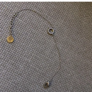Silverfärgat armband med cirkel och berlock - Elegant silverfärgat armband med en glittrig cirkel och en rund berlock med ingraverad symbol. Armbandet har en justerbar kedja för perfekt passform.