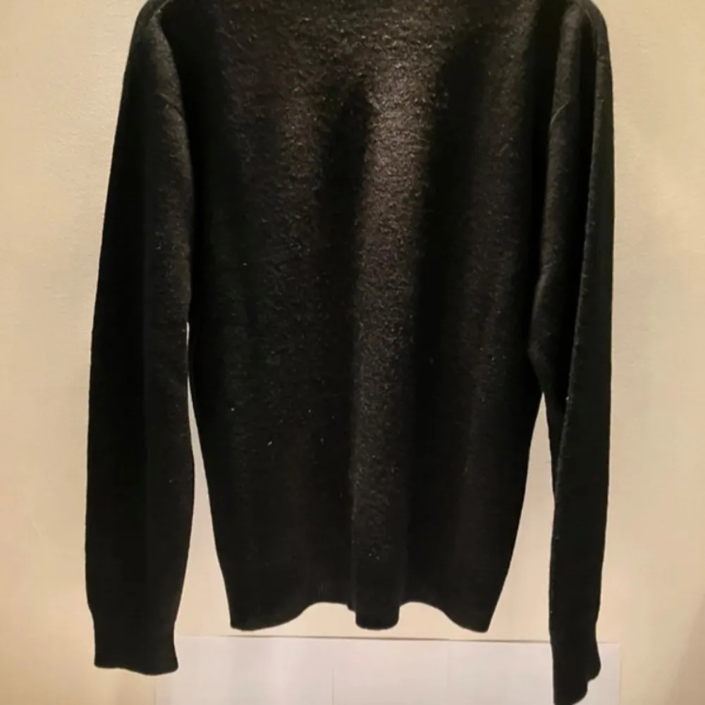 Snygg svart tröja från Lacoste med v-ringning och det klassiska krokodilmärket på bröstet. Perfekt för en stilren look. Tröjan är tillverkad i en mjuk och bekväm ullblandning.. Neuletakit & Villapaidat.