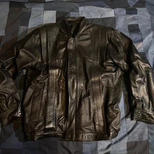 70-tals vintage skinnjacka - Snygg svart skinnjacka med stilrena linjer och dragkedja framtill. Jackan har axelvaddar. Man kan se på lädret att de är gammalt läder och inget nytt. Inga defekter! Dm vid frågor