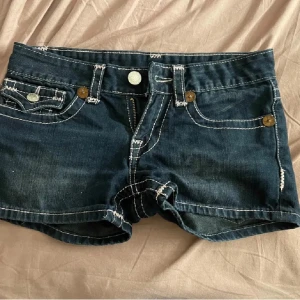 True Religion shorts - SKRIV INNAN DU KÖPER! LÅNADE BILDER! Snygga mörkblå jeansshorts från True Religion med ljusrosa sömmar. Säljer på grund av att de var för små. Lånade bilder från förra ägaren. 