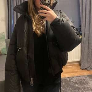 Svart pufferjacka - Säljer en svart pufferjacka från weekday i modellen Hedda. Jackan har en hög krage och långa ärmar, perfekt för kyliga dagar. Säljs då den inte används längre.🩷