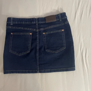 Mörkblå jeanskjol från Perfect Jeans - Säljer en snygg mörkblå jeanskjol från Perfect Jeans. Kjolen är i storlek S och har en klassisk femficksdesign med två bakfickor och tre framfickor. Den har en dragkedja och knapp framtill för enkel på- och avtagning. Perfekt för både vardag och fest!