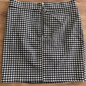 Svartvit rutig kjol med dragkedja - Säljer en superfin svartvit rutig kjol med dragkedja fram. Kjolen är kort och har en tight passform som framhäver figuren. Perfekt för både vardag och fest! 🖤🤍