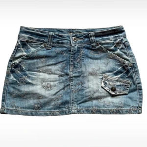 Super snygg jeanskjol💗 - Säljer en snygg jeanskjol i storlek S. Kjolen har coola broderade mönster och en liten ficka med knappdetalj fram. Midjemåttet är 35,5cm. Passar bra till både vardag och fest! Skriv om ni har någon fråga.