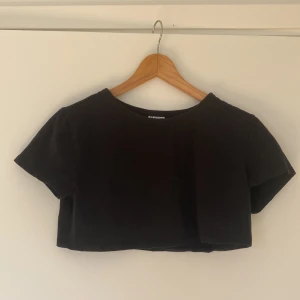 Kort T-shirt  - Kort svart T-shirt. Står att den är i strl XL men är antagligen felmärkt. Skulle gissa på att den nog är i strl XS eller S Knappt använd, nyskick.