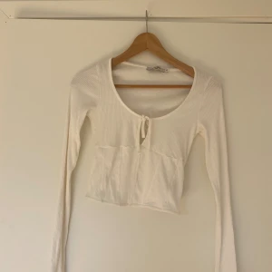 Vit långärmad tröja - Uringad vit ribbad långärmad med detalj på framsidan. Man kan spänna åt banden framtill för att göra ”hålet” mindre. Aldrig använd, nyskick💗