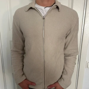 Beige Stickad Kofta Med Dragkedja - Säljer en snygg beige stickad kofta med dragkedja. Tröjan är i nyskick och är supermjuk och bekväm. Storleken är XS men den passar exakt som M och kanske som S. Modellen är 182 cm och väger 75 kg. Pris går att diskuteras!