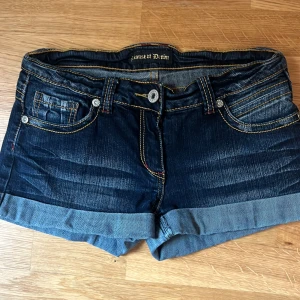 Mörkblå jeansshorts från House of Denim - Säljer ett par snygga mörkblå jeansshorts från House of Denim. De har en låg midja och är i nyskick. Shortsen har en klassisk femficksdesign med knappar och dragkedja framtill. Perfekta för sommaren!❤️❤️❤️ 