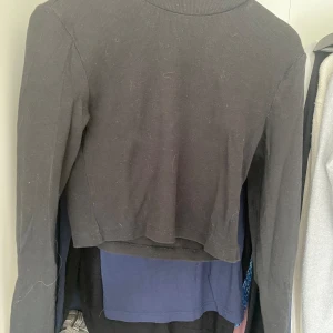 Svart croppad tröja - Säljer en svart croppad tröja i storlek S. Tröjan är långärmad och har en ribbad textur. Perfekt för höst och vinter, och kan stylas med både jeans och kjol. Den är i välanvänt skick men fortfarande snygg och användbar.