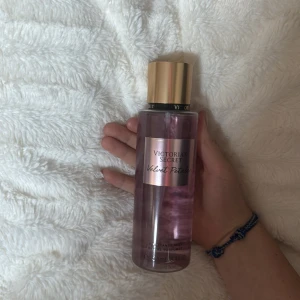 Victoria's Secret Velvet Petals Body Mist - Säljer en Victoria's Secret Velvet Petals body mist. Flaskan är genomskinlig med en rosa ton och har en guldig kork. Doften är en blandning av frodiga blommor och mandelmjölk, vilket ger en söt och blommig doft. Perfekt för daglig användning eller som en present! Väldigt lite använd 