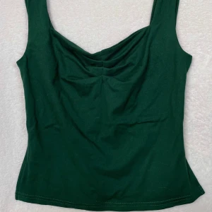 Grön topp - Grön söt topp. Toppen är rynkad vid bröstet och slits vid sidorna längst ned vid toppen som ger en söt detalj!!  Passar till alla tillfällen och är använd sparsamt💚💚