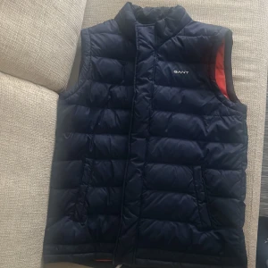 Marinblå Gant väst STL S/170 - Säljer min gamla väst som är marinblå och orange på insidan. Passar typ 170 cm eller om man har storlek S. Inköpt förra sommaren.  Inga skador på den alls. Nypris 1599 kan gå ner i pris vid snabb affär