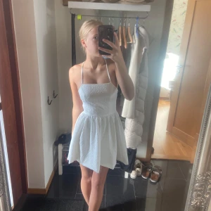 Vit klänning - Köpte denna klänningen till min skolavslutning och har använts två gånger. Jätte fin klänning och den är i fint skick. Öppen där bak med snören och den har en dragkedja nedanför. Lite blommigt material. Från SHEIN.