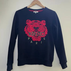 Svart tröja med röd tiger från Kenzo - Säljer tröja från Kenzo med tight passform. Perfekt skick endast använd några gånger 