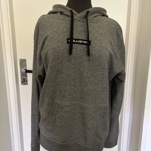 Grå hoodie från Hollister - Säljer en riktigt skön grå hoodie från Hollister. Perfekt för kyliga dagar eller bara för att chilla hemma. Den är i nyskick