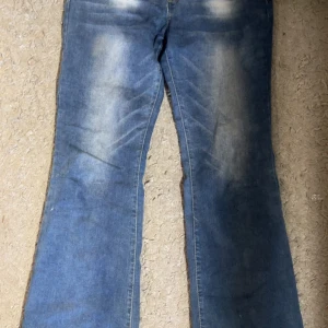 Blå jeans i bootcut-stil - Säljer ett par blå bootcut jeans i storlek S. De är tillverkade av 67% bomull, 31% polyester och 1% spandex, vilket gör dem både bekväma och stretchiga. Perfekta för en avslappnad look!