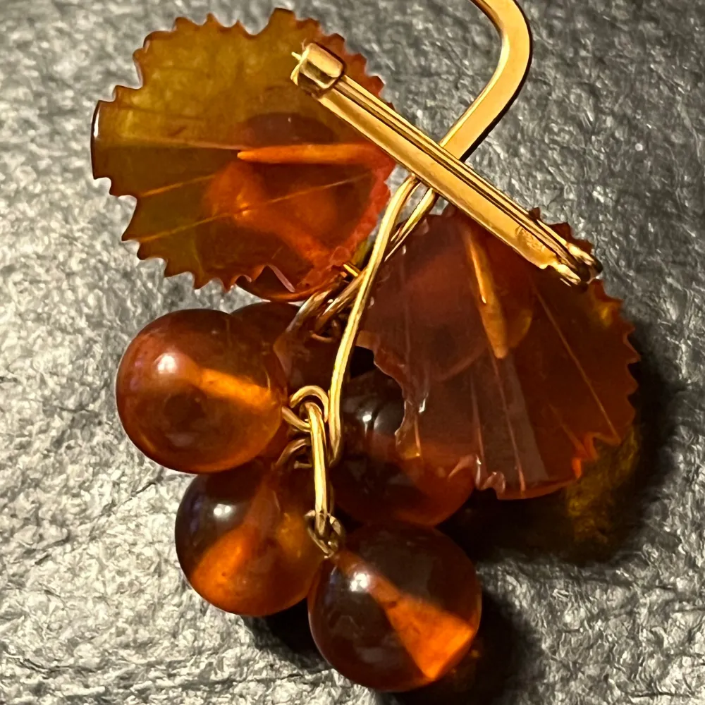 Unik brosch i form av en druvklase med bärnstensfärgade pärlor och detaljer i guld. Perfekt för att ge en elegant touch till din outfit.. Asusteet.