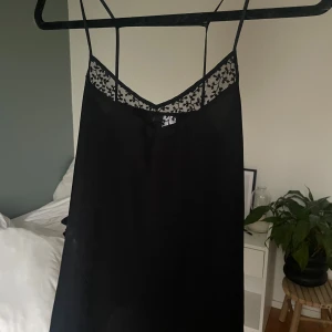Svart linne med spetsdetaljer - Säljer ett svart linne med tunna axelband och  spetsdetalj upptill. 
