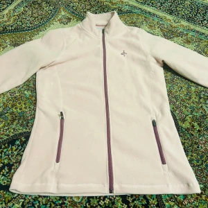 Ljusrosa fleecetröja från Cross Sportswear - Mysig ljusrosa fleecetröja från Cross Sportswear med dragkedja framtill och två praktiska fickor med dragkedjor. Perfekt för kyliga dagar.