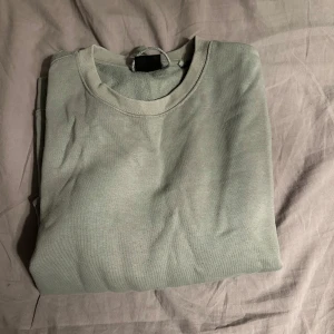 Mint grön från Pull&Bear - Säljer en stilren grå hoodie från Pull&Bear. Den har en klassisk design med långa ärmar och en bekväm passform. Perfekt för en avslappnad look. Använd några gången så den är lite missfärgad men inget man tänker på!