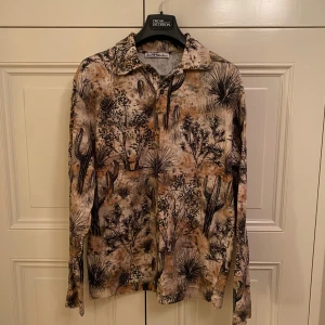 Acne Studios Långärmad Piké - Säljer en långärmad piké från Acne Studios med ett unikt mönster. Perfekt mönster för sommarn och för dig som vill sticka ut med stil! Står S (180) men den passar som M 