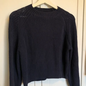 Mörkblå stickad tröja från Monki - Säljer en snygg mörkblå stickad tröja från Monki. Tröjan har en ribbad design med långa ärmar och rund halsringning. Perfekt för kyligare dagar!