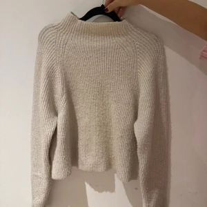 Beige stickad tröja från Kappahl - Säljer en mysig beige stickad tröja från Kappahl i storlek S. Tröjan har en ribbad design och långa ärmar, perfekt för kyligare dagar. Materialet består av polyester, akryl och en liten del ull för extra värme.