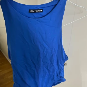 Blå ärmlös bodysuit från Zara - Säljer en stilren blå ärmlös bodysuit från Zara. Perfekt för lager-på-lager eller att bära som den är. Den har en enkel design med rund halsringning.
