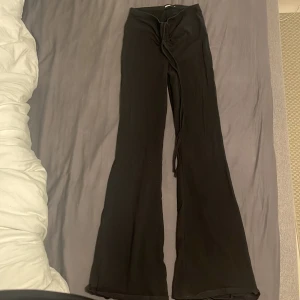 Svarta byxor med knytning från Bik Bok - Snygga svarta byxor från Bik Bok med knytning framtill. Byxorna har en bootcut-stil som ger en trendig look. Perfekta för att skapa en stilren outfit.