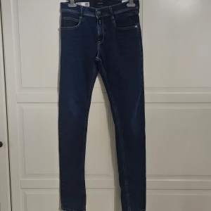 Blå Replay Hyperflex Jeans - Snygga blå Replay Hyperflex jeans med en slim passform. De har en klassisk femficksdesign och är tillverkade i ett stretchigt material för extra komfort. Perfekta för en stilren look.                                 Storlek: 28/30                                                          säljer dem pågrund av att dem är för små/ har aldrig använt dem                                    pris kan diskuteras 
