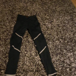 Svarta träningsleggings med reflexdetaljer - Snygga svarta träningsleggings med reflexdetaljer längs benen. Perfekta för kvällslöpning eller gymmet. De har en tight passform och är tillverkade i ett stretchigt material för bästa komfort och rörelsefrihet.