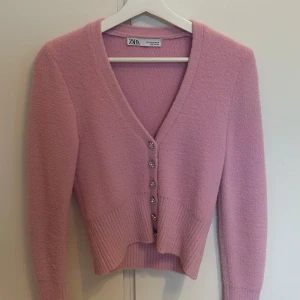 Rosa kofta från Zara - Säljer en söt rosa kofta från Zara med v-ringning och knappar framtill. Koftan är i ett mjukt material och har långa ärmar. 