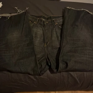 Svarta jeans med slitna detaljer - Säljer ett par svarta jeans som är avklippta längst ner. Dom är i super bra skick förutom längst nere vid hälen. Skicka om du har frågor!