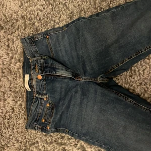 Blå jeans från Gina Tricot - Snygga blå jeans från Gina Tricot, modell Molly. De har en tight passform och är perfekta för en stilren look. Klassisk design med fem fickor och knappgylf.