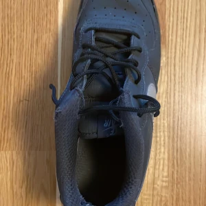 Svarta Nike Air Force sneakers storlek 38.5 men passar lätt 40.5 deras storlekar är lite konstiga - Säljer ett par klassiska svarta Nike Air Force sneakers i bra skick. De har en snygg svart färg med vit swoosh och snörning. Perfekta för vardagsbruk och streetwear-stil. Sulan är i gott skick och ger bra grepp.