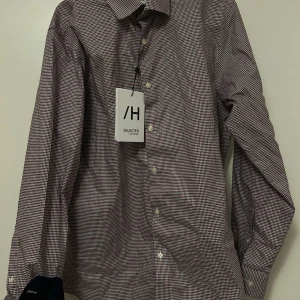 Rutig skjorta från Selected Homme - Snygg rutig skjorta från Selected Homme i en klassisk design. Skjortan har långa ärmar och knappar framtill. Perfekt för en stilren look.