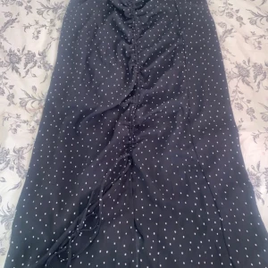 Svart prickig kjol från Vero Moda - Säljer en superfin svart kjol med vita prickar från Vero Moda. Kjolen har en snygg snörning framtill som ger en cool detalj. Perfekt för både vardag och fest! 🖤