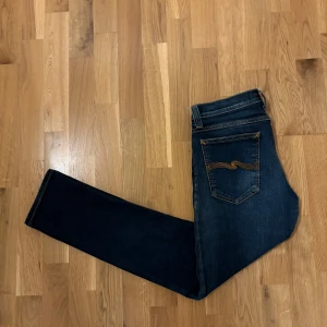 Mörkblå jeans - Säljer ett par mörkblå jeans i mycket bra skick. De har en slim passform och är perfekta för både vardag och fest. Jeansen har klassiska fem fickor och snygga sömmar på bakfickorna. De är tillverkade i ett bekvämt denimtyg som sitter skönt hela dagen. Jeansen är lite kortare på länden så dom sitter mer som L31. 