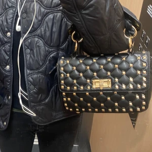 väska med nitar - Snygg svart väskaef nitar. Valentino lknande väska i helt ok skick då lädret  inte är i toppen skick. Köpt på plick 