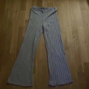 Grå randiga mysbyxor - Säljer ett par snygga grå randiga mysbyxor i bra skick. De har en  bra passform och är perfekta för mysiga hemmakvällar. Byxorna är högmidjade och har en skön och stilren design. Perfekta för höst och vår!
