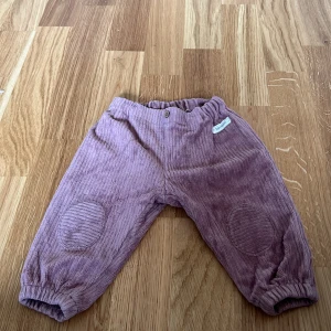 Lila manchesterbyxor från Newbie - Säljer ett par söta lila manchesterbyxor från Newbie för barn i storlek 62. Byxorna har resår i midjan och vid bensluten för extra komfort. Perfekta för de små under höst och vår.