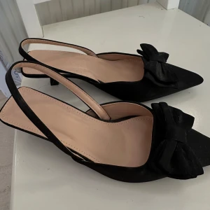 Klackar - Supersnygga svarta klackar med rosett framtill, aldrig använda, i stl 38/39. Låg klack🫶🏼🫶🏼