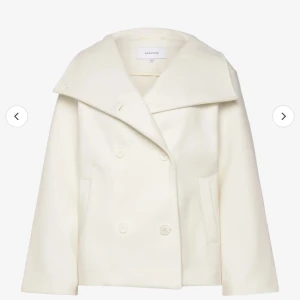Vit kappa från bubbelrom  - Säljer en stilren vit/beige kappa från bubbelrom i mycket bra skick. Den har en klassisk design med stora slag och knappar framtill. Perfekt för höst och vår.