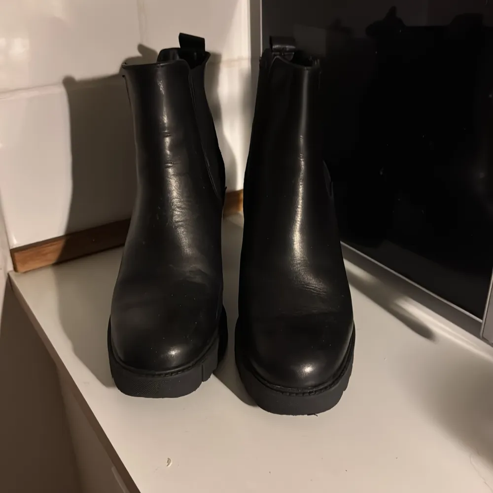 Säljer ett par snygga svarta boots från Tamaris i skinn. De har en rejäl klack och är perfekta för höst och vinter. Skorna har en stilren design med elastiska paneler på sidorna för enkel på- och avtagning. Perfekta för både vardag och fest! Storlek 37, dyra vid inköp så respektera priset & självklart står kund för egen frakt 📦 . Skor.