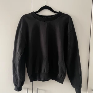 Svart sweatshirt - Säljer en klassisk svart sweatshirt i mycket bra skick. Den har en normal passform med långa ärmar och ribbade muddar vid ärmslut och nederkant. Perfekt för både höst och vinter, och funkar lika bra till vardags som till en avslappnad fest. Ett måste i garderoben! 🖤