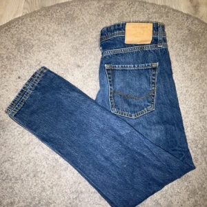 Blå jeansbyxor Relaxed/Chris - Säljer ett par blå jeansbyxor från Jack & Jones i modellen Relaxed/Chris. De har en avslappnad passform och klassisk femficksdesign. Perfekta för en casual look.