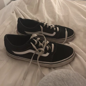 Svarta sneakers från Vans - Säljer ett par klassiska svarta Vans sneakers med vit sula och snörning. Skorna kostar 450kr original pris men säljer för 150kr. Dem är i storlek 39 och använts max 10 gånger, alltså ganska bra skick!